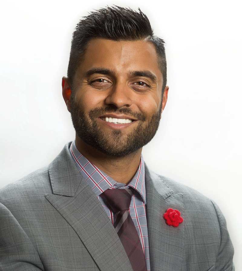 Headshot of Irwin Sra wearing grey blazer, patterned dress shirt, and burgundy tie