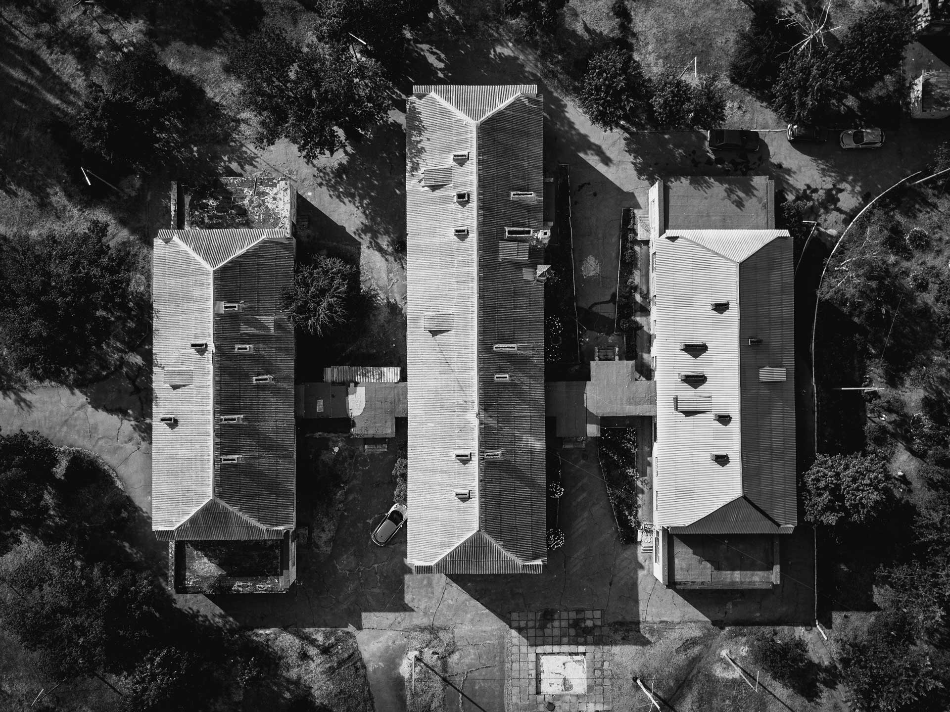 Black-and-white aerial view of the roofs of 3 homes